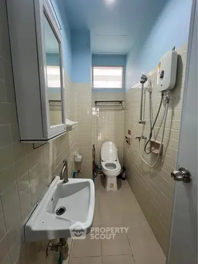 Compact bathroom with modern fixtures and overhead shower in cozy real estate property.