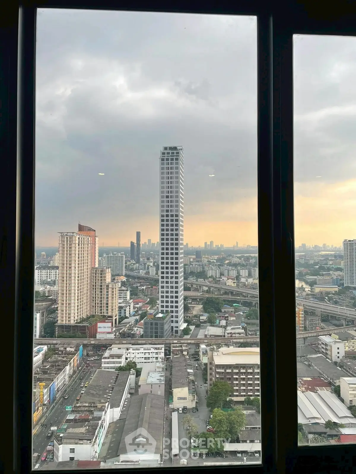 Stunning cityscape view from high-rise window showcasing urban skyline at sunset.