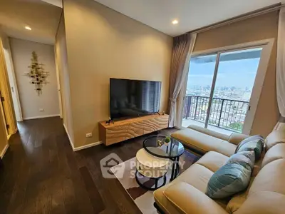 Modern living room with large TV and city view balcony, featuring elegant decor and cozy seating.