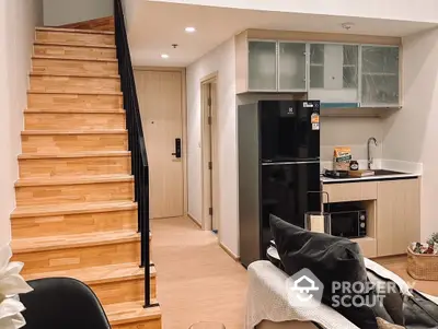 Charming modern living space with sleek wooden staircase, cozy sitting area, and a compact kitchenette, perfect for urban living.