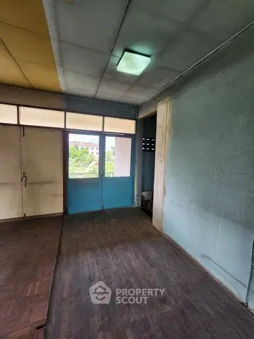 Spacious room with wooden flooring and large windows for natural light.
