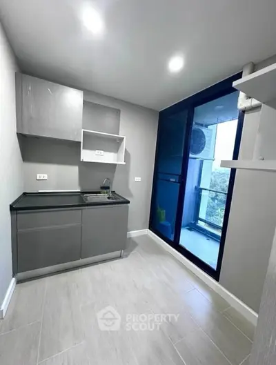 Modern kitchen with sleek cabinetry and balcony access in a stylish apartment.