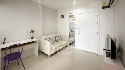 Modern living room with sleek white sofa, minimalist decor, and a compact workspace.