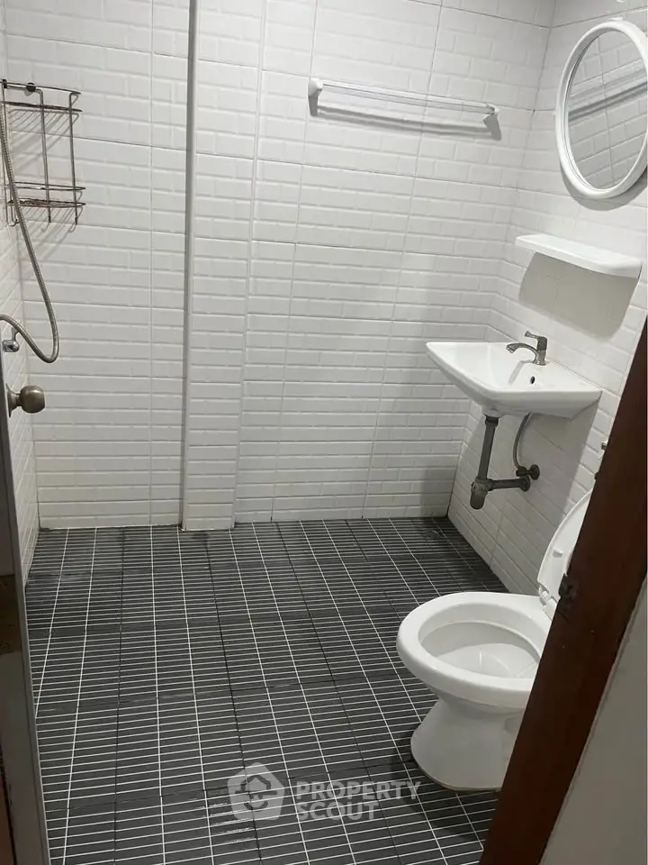 Modern minimalist bathroom with white tiles and sleek fixtures.