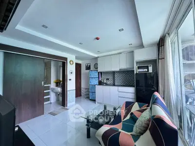 Modern open-layout living room with stylish kitchen and colorful sofa in a bright apartment.