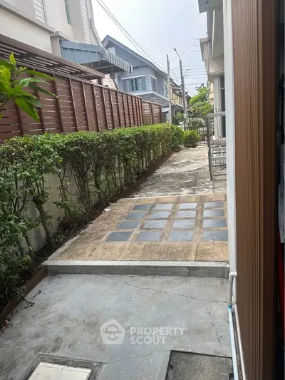 Charming residential pathway with lush greenery and modern architecture, perfect for serene living.