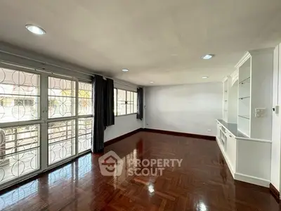 Spacious living room with hardwood floors and built-in shelving, ample natural light.