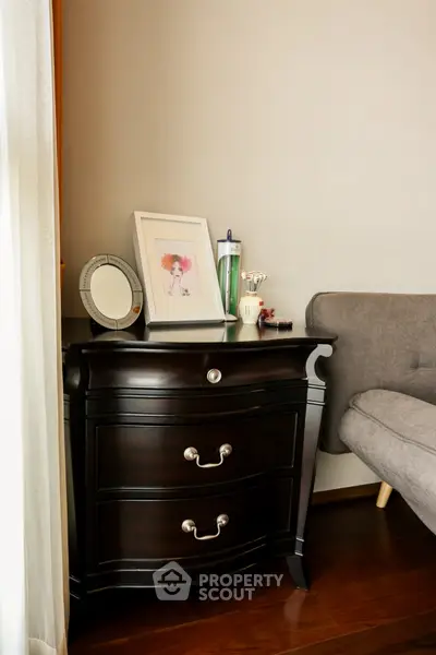 Elegant corner with dark wood dresser and cozy gray sofa in stylish living room.