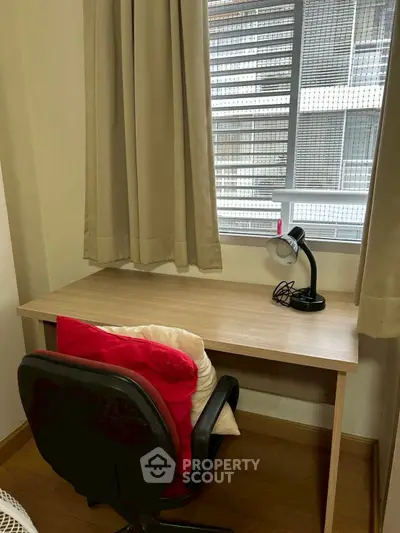 Cozy study nook with desk, chair, and lamp by window in modern apartment.