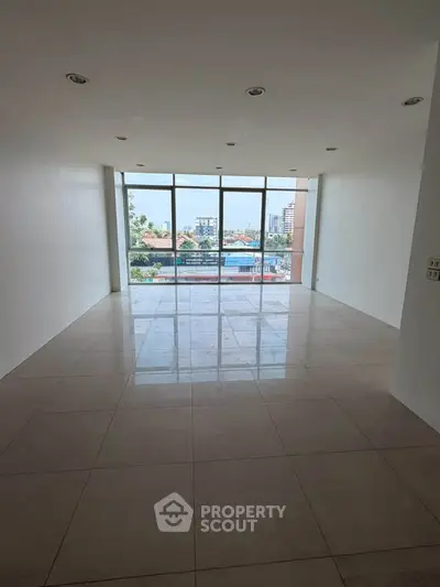 Spacious empty room with large windows offering a panoramic city view, perfect for customization.