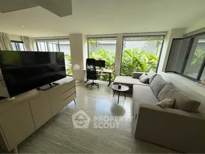 Spacious living room with modern decor and large windows overlooking lush greenery.