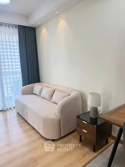 Modern living room with cozy beige sofa and elegant wooden side table, featuring floor-to-ceiling windows.