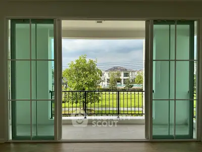 Spacious balcony with sliding glass doors and scenic view of lush greenery.