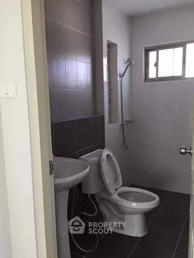 Modern bathroom with sleek fixtures and neutral tiles, featuring a shower and toilet.