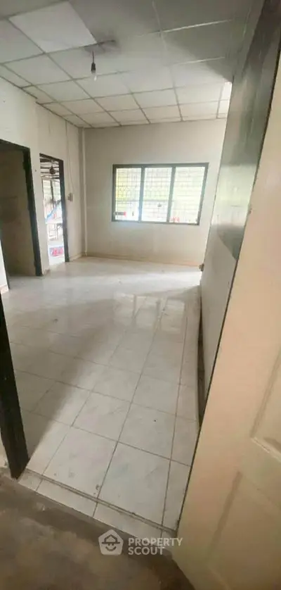 Spacious empty room with tiled flooring and large windows, ideal for customization.