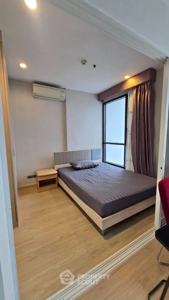 Modern bedroom with wooden flooring and large window in a stylish apartment