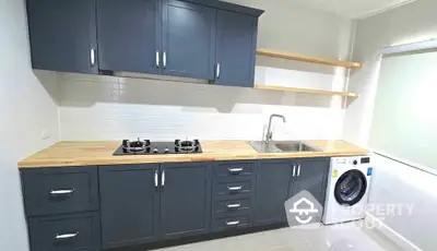 Modern kitchen with dark cabinets, gas stove, and washing machine