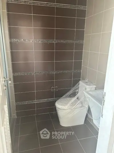 Modern bathroom with sleek tile design and new toilet installation.