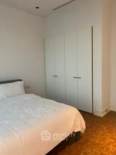 Cozy bedroom with white bedding and built-in wardrobe, perfect for restful nights.