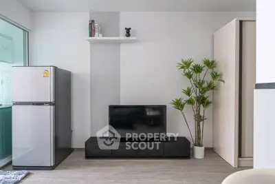 Modern living room with sleek TV stand, fridge, and stylish decor