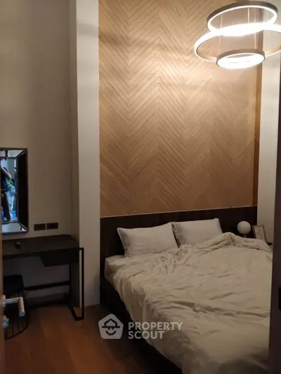 Cozy bedroom with modern lighting and stylish wood accent wall, perfect for relaxation.