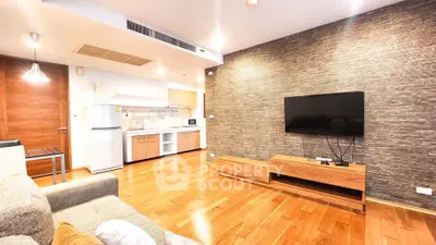 Modern living room with wooden flooring, stylish TV setup, and compact kitchen area.