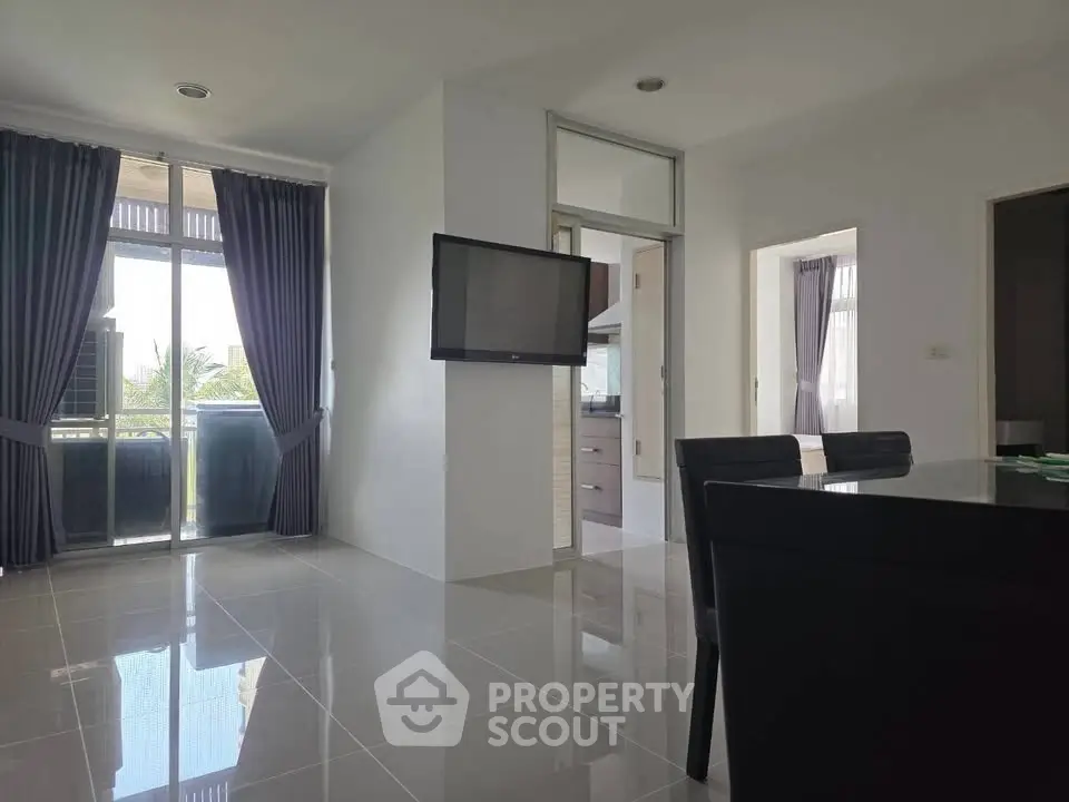 Modern living room with sleek design and natural light, featuring a wall-mounted TV and elegant dining area.