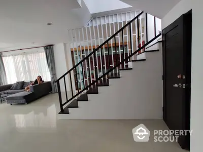 Spacious and modern living area with sleek staircase, glossy floor tiles, and abundant natural light, perfect for family gatherings and stylish living.