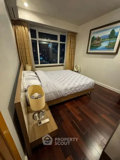 Cozy bedroom with city view, wooden flooring, and elegant decor.