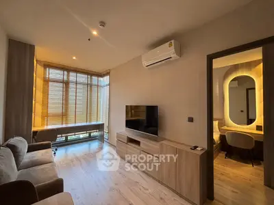 Modern living room with wooden flooring, cozy seating, and large windows with blinds.