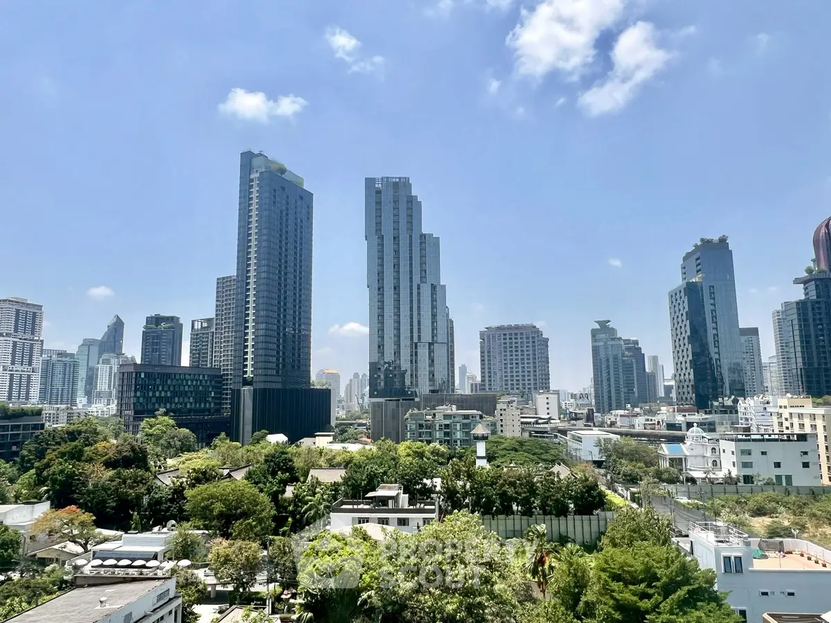 Stunning cityscape view of modern skyscrapers and lush greenery under a clear blue sky.