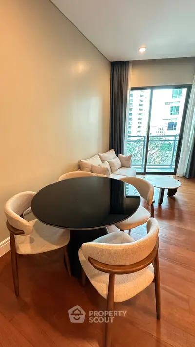 Modern living room with elegant dining set and cozy sofa near balcony with city view.