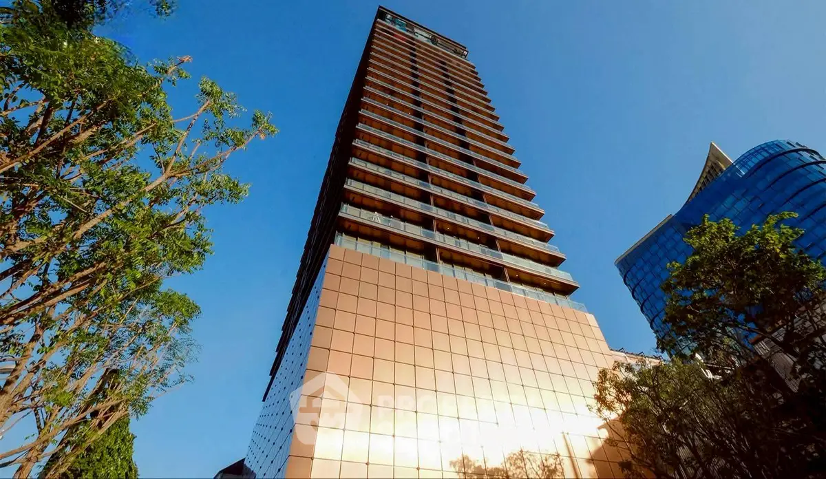 Stunning modern high-rise building with reflective glass facade and lush greenery.