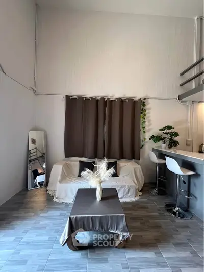 Modern living room with high ceiling, cozy sofa, and stylish bar stools in open layout.