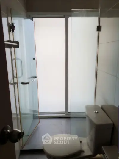 Modern bathroom with glass shower and frosted window for privacy.