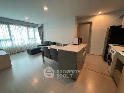 Modern open-plan living room with kitchen, featuring sleek furniture and natural light.