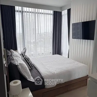 Modern bedroom with large windows and wall-mounted TV in a stylish apartment.