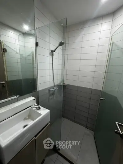 Modern bathroom with glass shower and sleek sink in contemporary apartment.