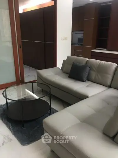Modern living room with sleek gray sofa and glass coffee table in stylish apartment.