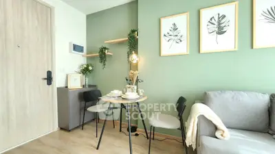 Charming living room with modern decor, green accent wall, and cozy dining area in a stylish apartment.