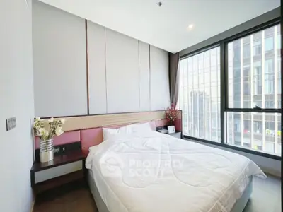 Modern bedroom with large windows and city view, featuring elegant decor and cozy bedding.