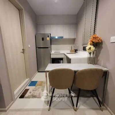 Modern compact kitchen with sleek appliances and cozy dining area in stylish apartment.
