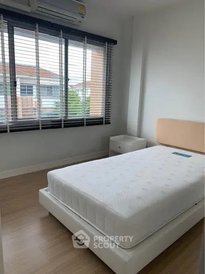 Bright bedroom with large window and modern furnishings, perfect for a cozy and comfortable living space.