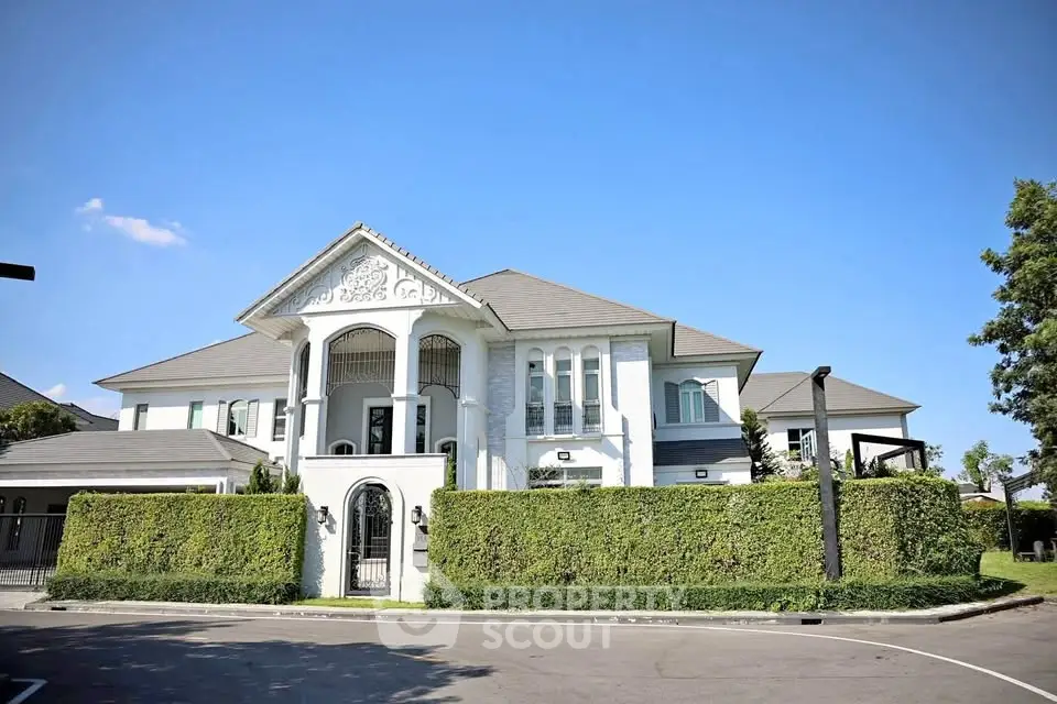 Luxurious white mansion with elegant architecture and lush greenery in a serene neighborhood.