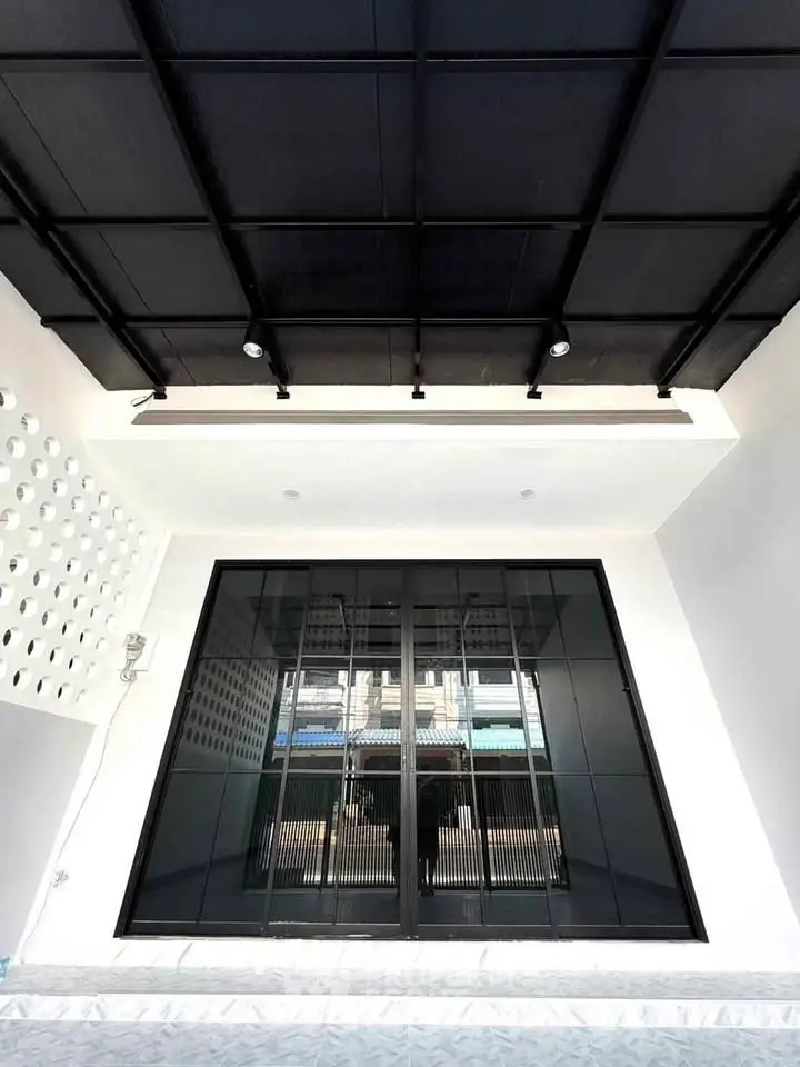 Modern architectural entrance with sleek black sliding doors and stylish ceiling design.