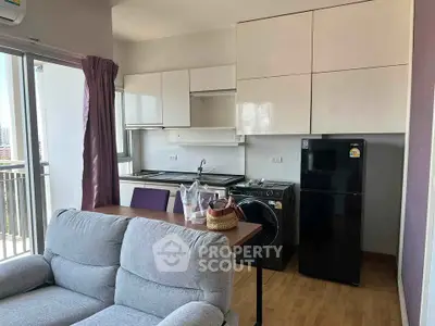 Modern apartment kitchen with sleek cabinets, washing machine, and fridge, adjacent to cozy living area with balcony view.