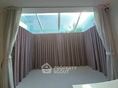 Spacious room with large windows and elegant curtains, perfect for natural light.