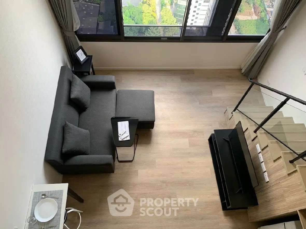 Modern loft apartment with stylish living room and staircase, featuring large windows and city view.