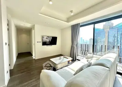 Modern living room with large windows and city view, featuring sleek furniture and natural light.