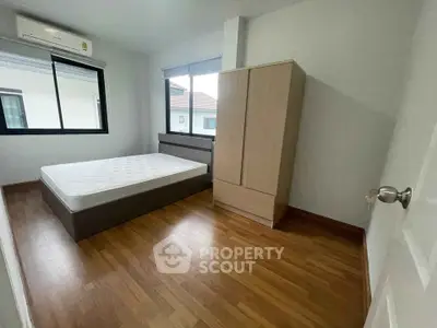 Spacious bedroom with wooden flooring and large windows in a modern home
